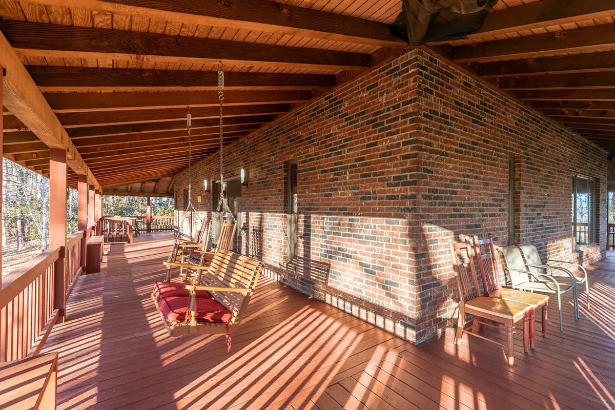 An inviting outdoor space featuring comfortable swing chairs set against a rustic brick wall, with wooden flooring underfoot. The area is surrounded by nature, making it an ideal spot for relaxing or enjoying the fresh mountain air. This space visually connects to the outdoors and has an atmosphere of tranquility, perfect for spending time with pets or unwinding after a day of adventure.