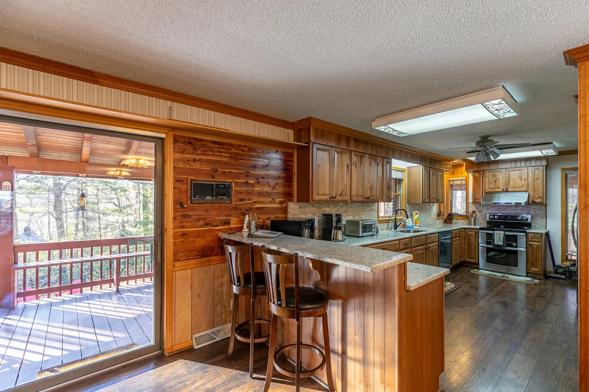 A welcoming kitchen scene with a generous island, bar stools, wood paneling, and a large window overlooking the outdoors. The setting encourages cooking, socializing, and enjoying the view while preparing family recipes or morning coffee.
