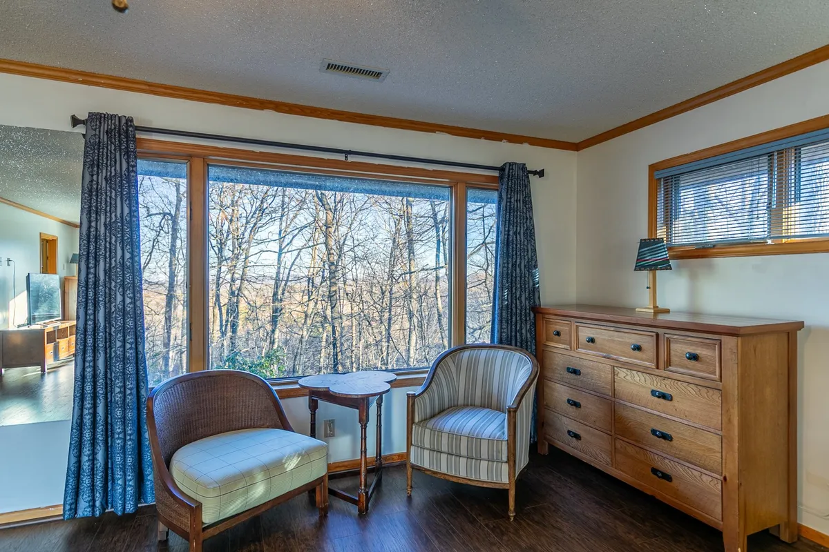A tranquil corner with two armchairs by a large window, offering a scenic view of the outdoors. The space is set up for reading, sipping coffee, or quiet reflection while enjoying seasonal changes—a perfect spot for unwinding or finding work inspiration.